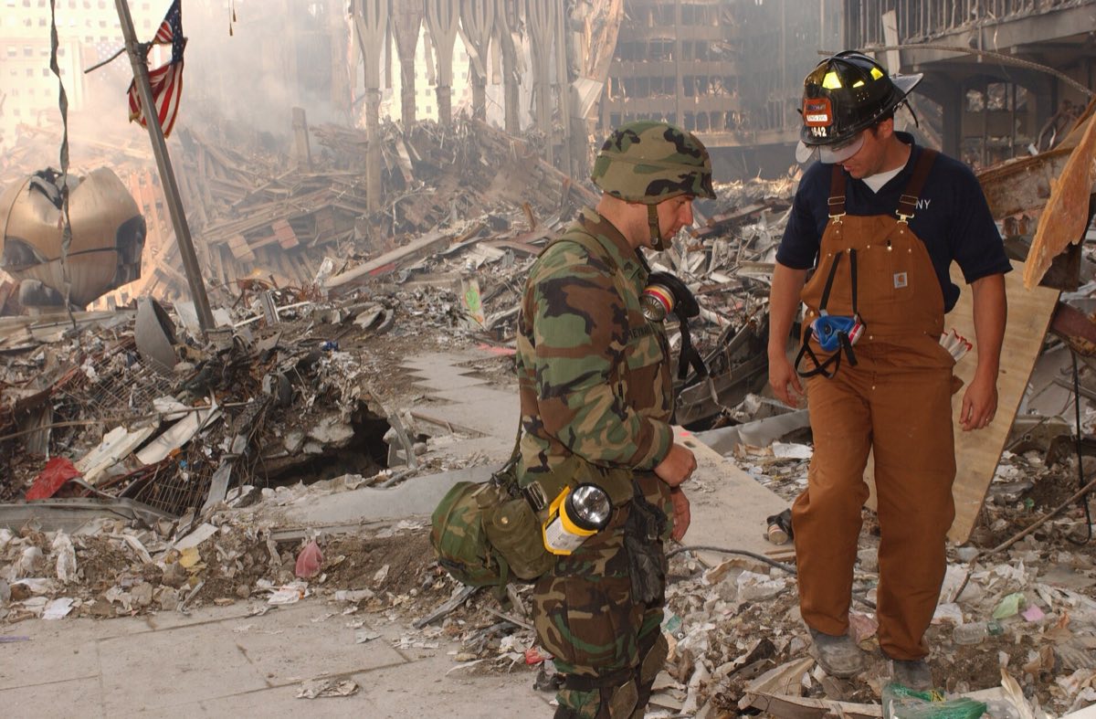 A New York Army National Guard soldier and an FDNY firefighter standing among the debris at Ground Zero