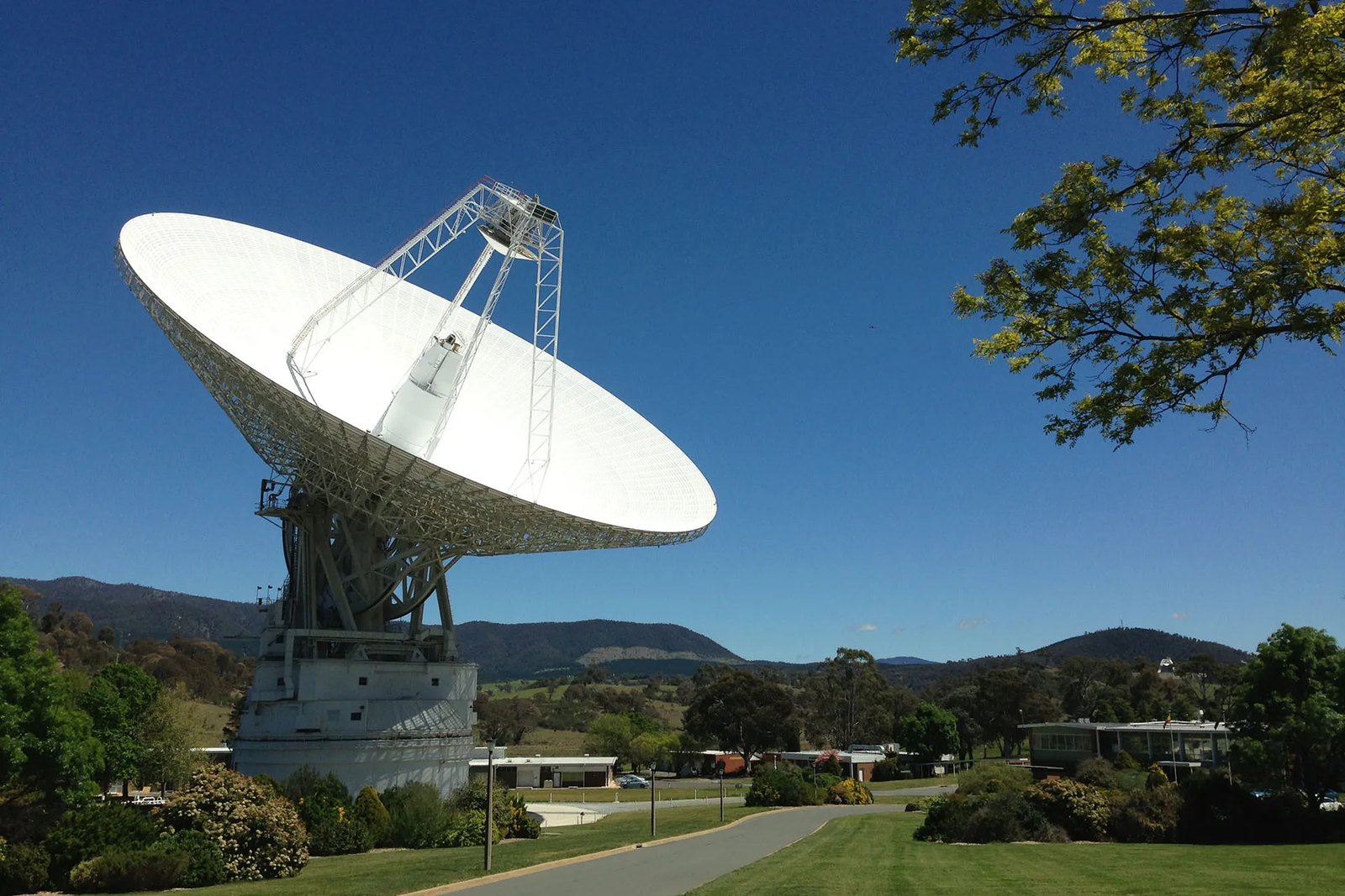 The 70-meter Deep Space Station 43 radio dish at Canberra pointed toward the sky, with hills behind it